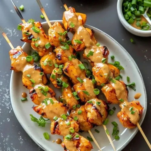 Delicious Bang Bang Chicken Skewers drizzled with spicy sauce