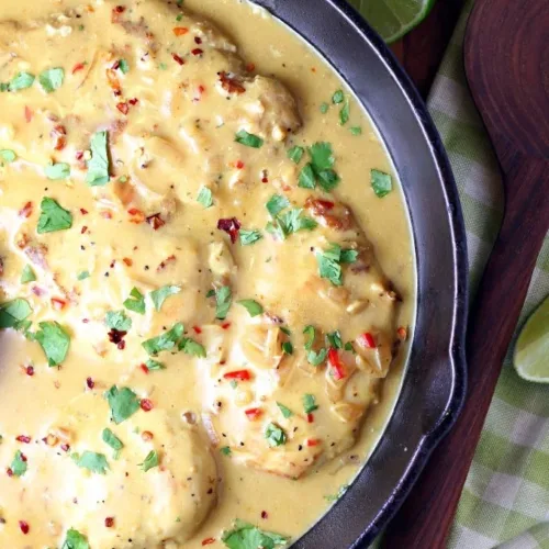 Creamy coconut lime chicken on a plate garnished with fresh herbs