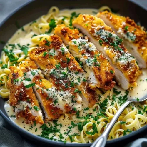 Crispy parmesan chicken drizzled with creamy garlic sauce on a plate
