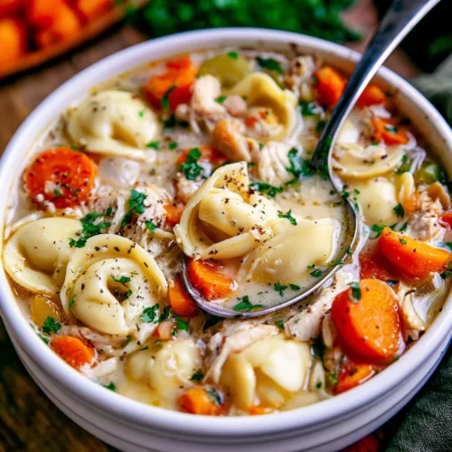 Slow cooker chicken tortellini soup served in a bowl with fresh herbs