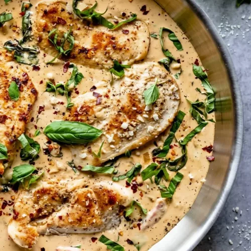 Creamy Parmesan Basil Chicken served in a bowl with herbs on the side
